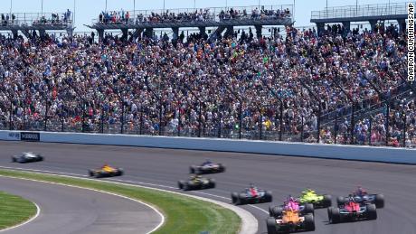 Fans watch as cars go through Turn 1 during the Indianapolis 500 auto race at Indianapolis Motor Speedway, May 30, 2021, in Indianapolis.