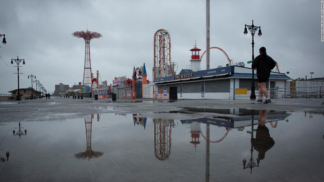 People visit the Coney Island boardwalk as rain falls in New York on Sunday.