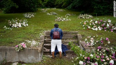 Linda Porter of Birmingham, Alabama, kneels at a makeshift memorial of flowers for the Tulsa Race Massacre at stairs leading to a now empty lot near the historic Greenwood district during centennial commemorations on Tuesday in Tulsa.