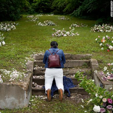 Linda Porter of Birmingham, Ala., kneels at a makeshift memorial of flowers for the Tulsa Race Massacre at stairs leading to a now empty lot near the historic Greenwood district during centennial commemorations of the massacre, Tuesday, June 1, 2021, in Tulsa, Okla. &quot;We came to remember,&quot; said Porter, who came to Tulsa for the centennial commemorations. (AP Photo/John Locher)