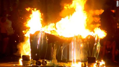 A trash container burns in the middle of a Minneapolis intersection on Thursday night.