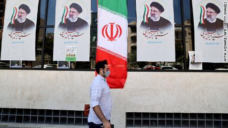 An Iranian man walks by posters of Raisi outside a campaign office in Tehran on June 7.