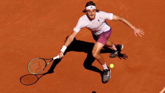 Tsitsipas stretches to play a forehand against Djokovic.