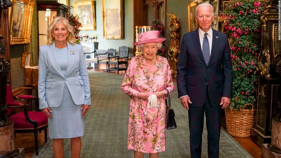 Britain&#39;s Queen Elizabeth II, center, poses with US President Joe Biden and first lady Jill Biden in the Grand Corridor of Windsor Castle in June 2021.