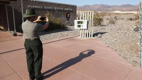 Un garde-parc prend une photo d'un thermomètre non officiel au Furnace Creek Visitor Center dans le parc national de Death Valley en Californie le 17 août 2020, un jour après que la température ait atteint 130 degrés.