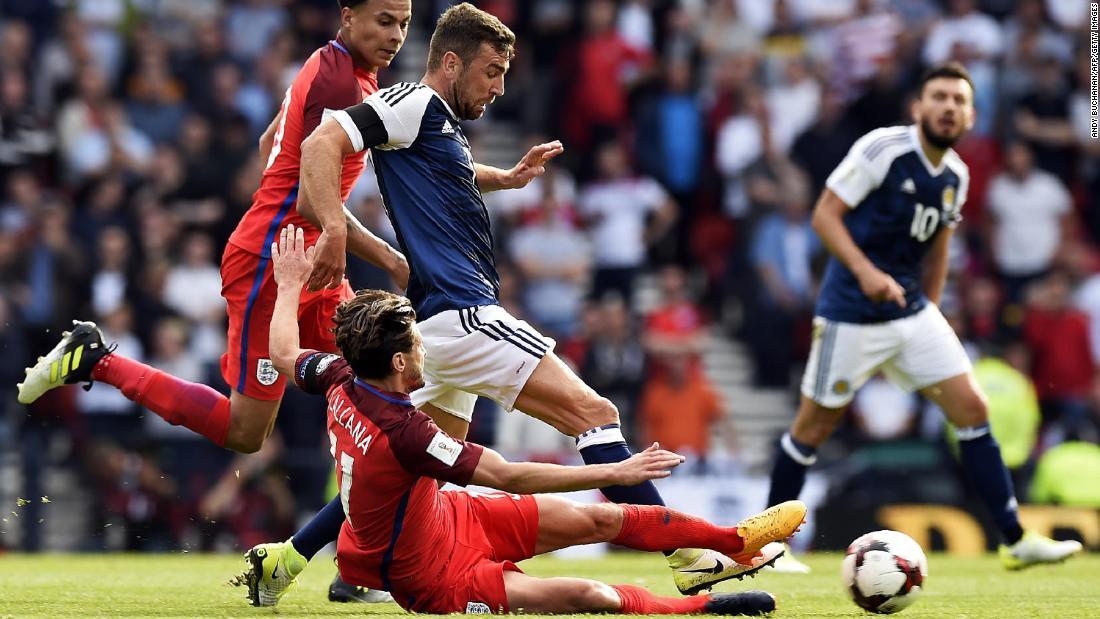 England&#39;s midfielder Adam Lallana slides in to tackle Scotland&#39;s midfielder James McArthur during the game that ended 2-2. 