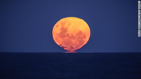 The strawberry moon rises over the ocean on Narrawallee Beach in New South Wales, Australia, on June 6, 2020.