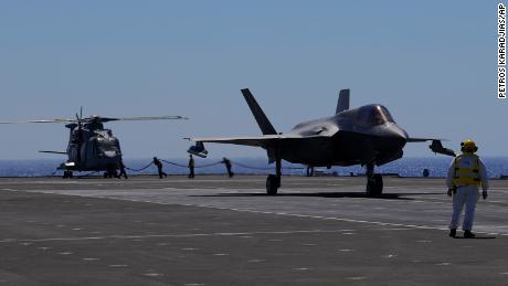 Crew members prepare an F-35B jet (right) for takeoff on the HMS Queen Elizabeth in the Mediterranean Sea on June 20, 2021.