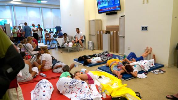 People lie on cots at the family reunification center in Surfside.