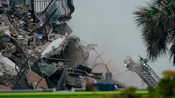 Firefighters use a ladder hose as smoke comes out of the rubble on Thursday.