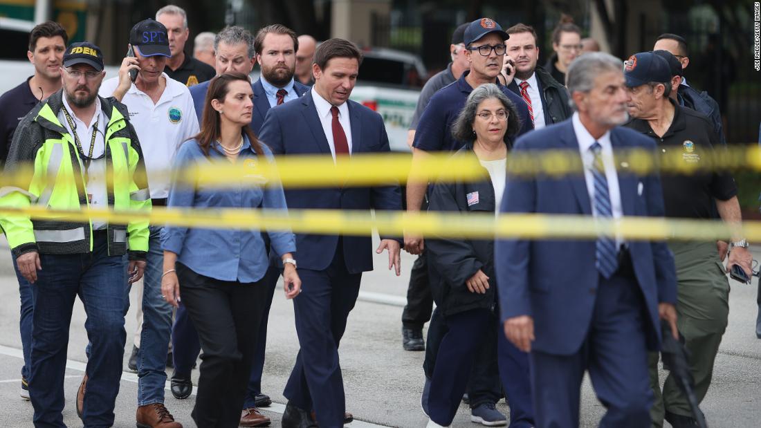 Florida Gov. Ron DeSantis, at center in the red tie, arrives to speak to the media on June 24. &quot;We still have hope to be able to identify additional survivors,&quot; DeSantis told reporters near the scene. &quot;The state of Florida, we&#39;re offering any assistance that we can.&quot;