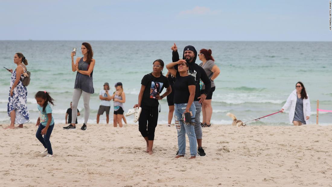 People on the beach look at the building after the partial collapse.