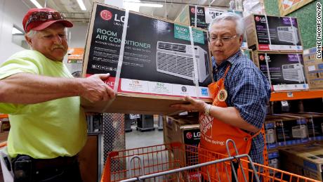 Home Depot store greeter Danny Olivar, right, lends a hand to a customer to heft an air conditioning unit from a rapidly declining stock ahead of an expected heat wave in Seattle in 2017.