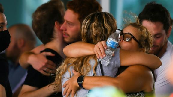 People hug Friday as they wait for news about their relatives at a community center in Surfside.