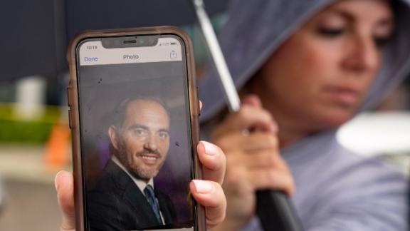 Toby Fried holds up a picture of her missing brother, Chaim Rosenberg, outside the Surfside Community Center on Friday.