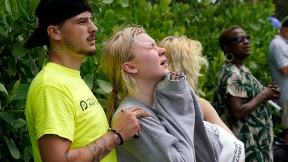Ariana Hevia, center, stands with Sean Wilt near the partially collapsed building on June 25. Hevia's mother, Cassandra Statton, lives in the building.