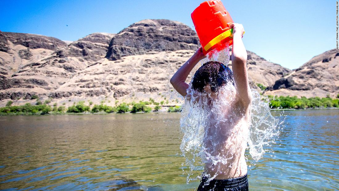 John Elizondo, 11, dumps a bucket of water over himself while playing in the Snake River at the edge of Asotin, Washington, on June 24.