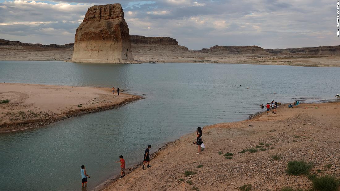 Park visitors in Big Water, Utah, walk on an area of Lake Powell that used to be underwater at Lone Rock Beach in June 2021.