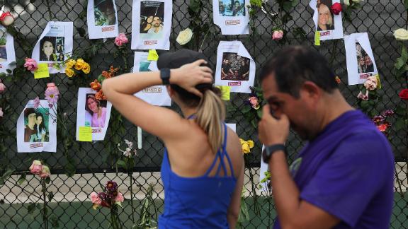 Passersby look at photos of missing people.