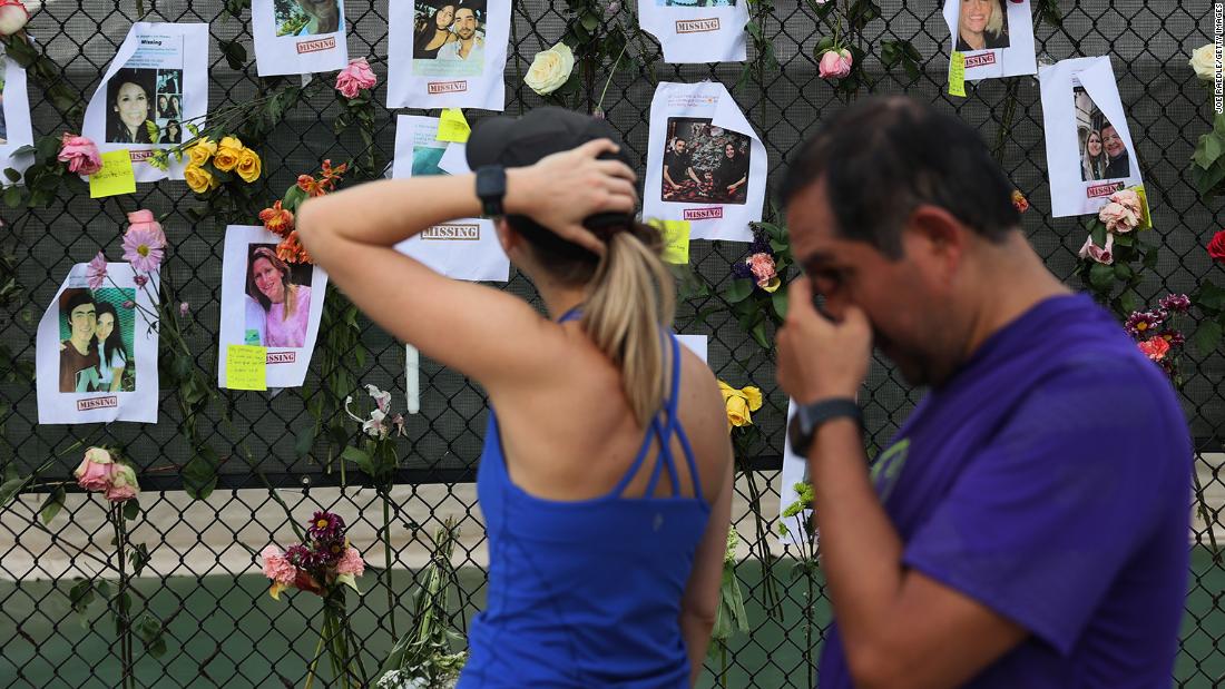 Passersby look at photos of missing people.