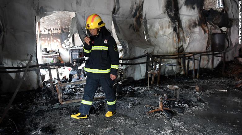 A firefighter investigates the fire scene at a martial arts school in China's Henan on June 25.