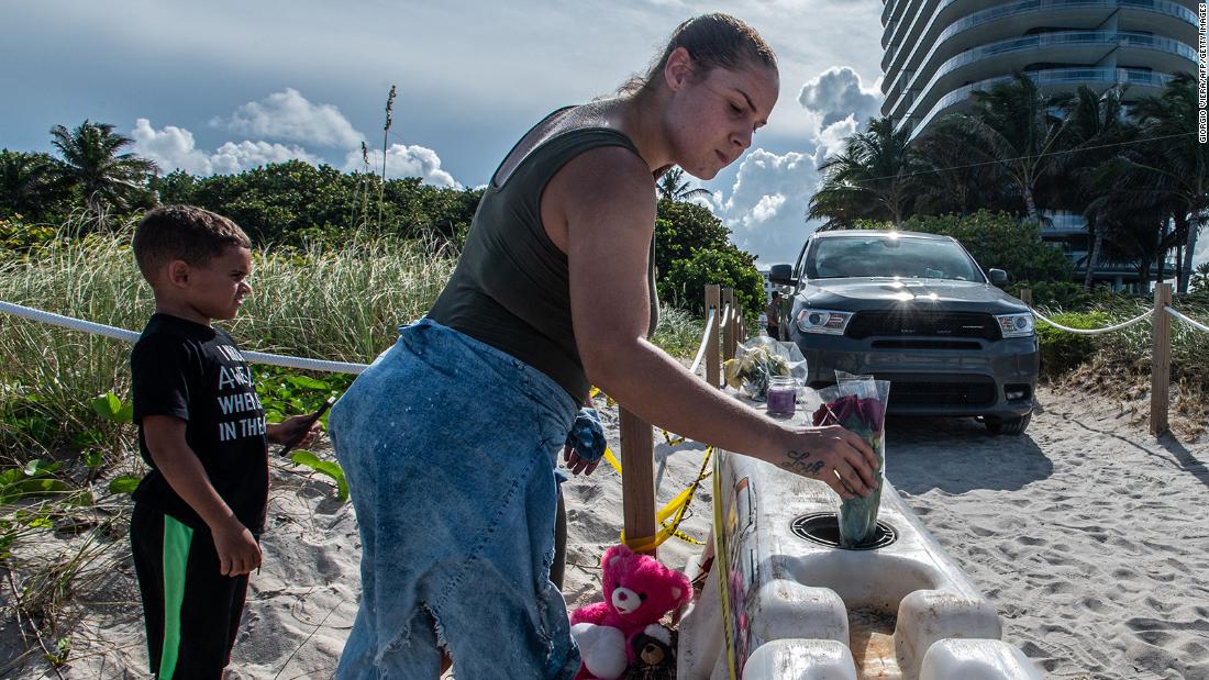 A woman puts flowers in a barricade as she pays her respects near the building.