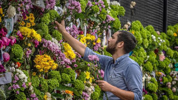 Leo Souto adds flowers to a memorial featuring photos of some of those lost in the partially collapsed building on June 28, in Surfside, Florida. 