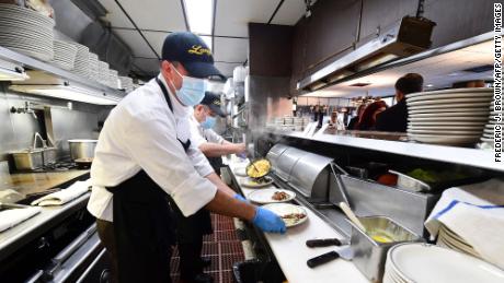 In this photo taken on June 15, 2021 kitchen staff continue wearing facemasks while preparing breakfast at Langer&#39;s Delicatessen-Restaurant in Los Angeles, California, on California&#39;s first day of fully reopening its economy after some fifteen months of Coronavirus pandemic restrictions.