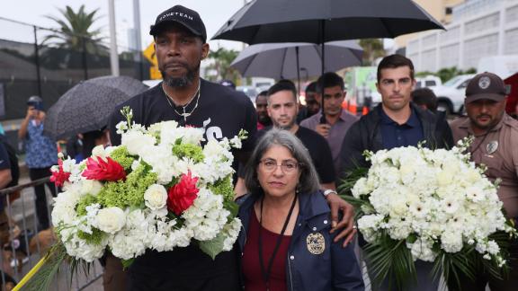 NBA basketball player Udonis Haslem, left, and Miami-Dade County Mayor Daniella Levine Cava arrive to pay their respects Wednesday at a memorial near the building.