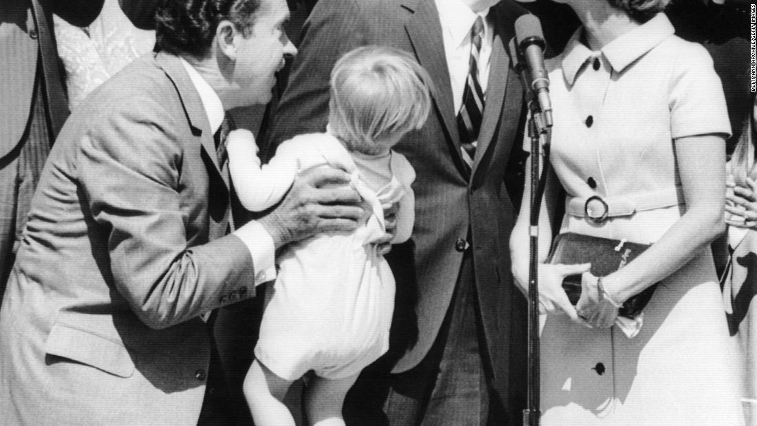 Rumsfeld is kissed by his wife, Joyce, after he was sworn in as director of the Office of Economic Opportunity in 1969. President Richard Nixon is holding their 2-year-old son, Nicholas.