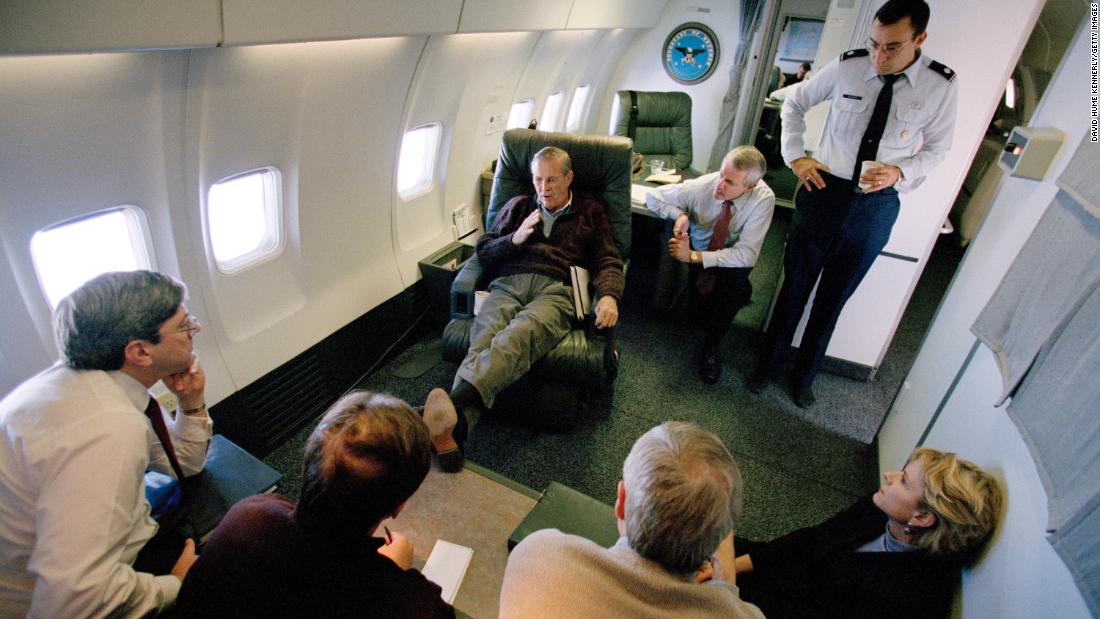 Rumsfeld talks to staff members aboard a plane en route to Saudi Arabia in October 2001.