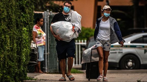 Residents of the Crestview Towers Condominium carry their belongings <a href=