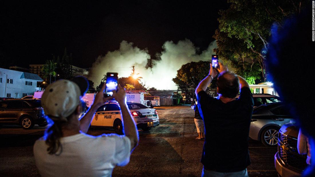 People watch a cloud of dust form as the rest of the building is demolished.