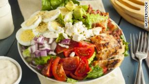 This hearty Cobb salad features chicken, bacon, t tomato, onions and eggs.