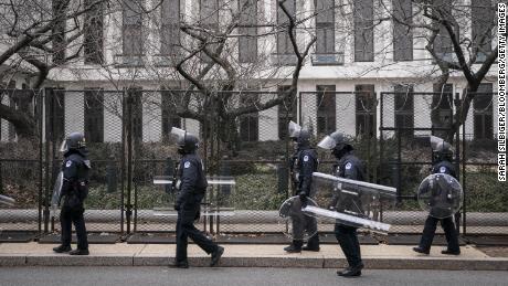 US Capitol police officers in protective riot gear walk by the fenced perimeter of the U.S. Capitol grounds in Washington, D.C., on Friday, January 29, 2021. 