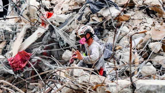 A member of the search and rescue team moves rubble at the site of the collapsed building in Surfside, Florida, Wednesday, July 7. 