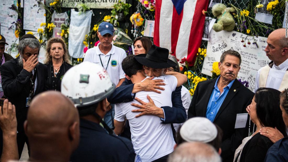 A member of Miami-Dade Fire Rescue hugs victims&#39; family members and friends at the memorial near the collapsed building.