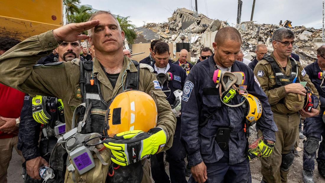 Workers gather for a moment of silence and prayer after it was announced that rescue efforts would transition to a recovery operation.