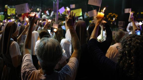 People lift their hands during a prayer at the memorial site for victims of the collapsed condo building.
