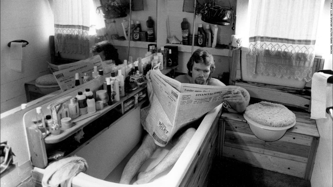 Branson reads the newspaper in a bathtub aboard his houseboat in London in 1984.