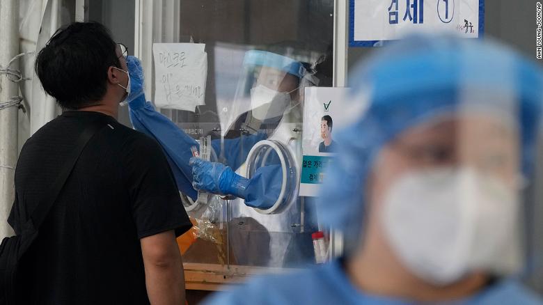 A medical worker in a booth takes a nasal sample from a man during Covid-19 testing at its site in Seoul on Thursday.