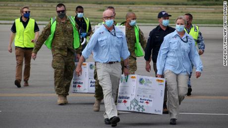 Australian officials carry boxes containing some 8,000 doses of the AstraZeneca vaccine at the Port Moresby international airport on March 23, 2021.