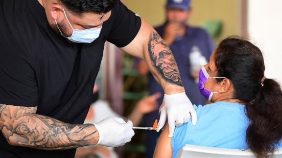 Respiratory therapist Robert Blas (L) from Veritas Vaccines administers the Pfizer Covid-19 vaccine at a mobile clinic to residents in an East Los Angeles neighborhood which has shown lower vaccination rates especially among the young on July 9, 2021 in Los Angeles, California. - Los Angeles County is seeing a surge in Covid-19 cases as the Delta variant spreads and brings rising alarm. (Photo by Frederic J. BROWN / AFP) (Photo by FREDERIC J. BROWN/AFP via Getty Images)