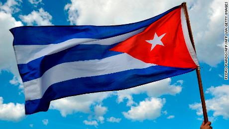 A person holds a Cuban national flag as Cubans arrive to pay their last respects to late revolutionary leader Fidel Castro at Revolution Square in Havana, on November 29, 2016. - A titan of the 20th century who beat the odds to endure into the 21st, Castro died late Friday after surviving 11 US administrations and hundreds of assassination attempts. No cause of death was given. Castro's ashes will go on a four-day island-wide procession starting Wednesday before being buried in the southeastern city of Santiago de Cuba on December 4. (Photo by PEDRO PARDO / AFP) (Photo by PEDRO PARDO/AFP via Getty Images)