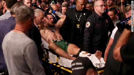 McGregor is carried out of the arena on a stretcher after injuring his ankle in the first round of his lightweight bout against Poirier.
