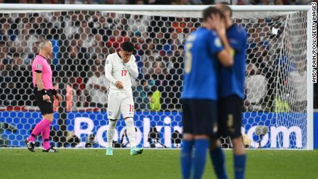 Manuel Locatelli and Giorgio Chiellini of Italy celebrate as Jadon Sancho looks dejected after missing England&#39;s fourth penalty.