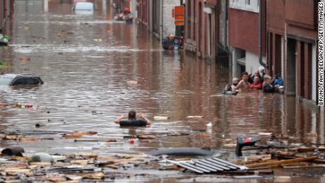Eine Frau versucht, nach starkem Regen in Lüttich, Belgien, eine überflutete Straße entlang zu gehen.
