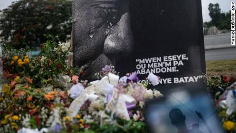 A man is reflected on a cellphone at a memorial outside the Presidential Palace in memory of slain President Jovenel Moise, in Port-au-Prince, Haiti, Wednesday, July 14, 2021.