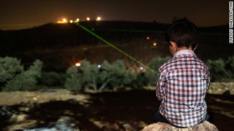 A Palestinian boy shines a green laser at the illegal settlement of Givat Evyatar, West Bank, on July 2.