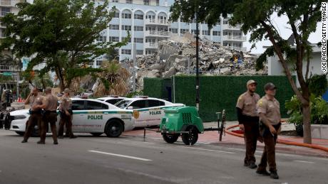 Miami-Dade police officers helping with the search and rescue stand near the completely collapsed 12-story Champlain Towers South on July 6, 2021 in Surfside, Florida. 